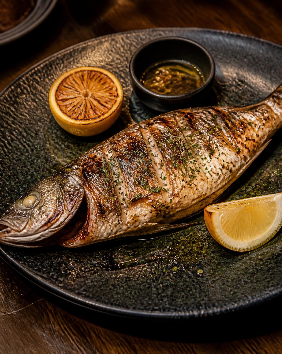 Pesce intero alla griglia servito in un piatto scuro